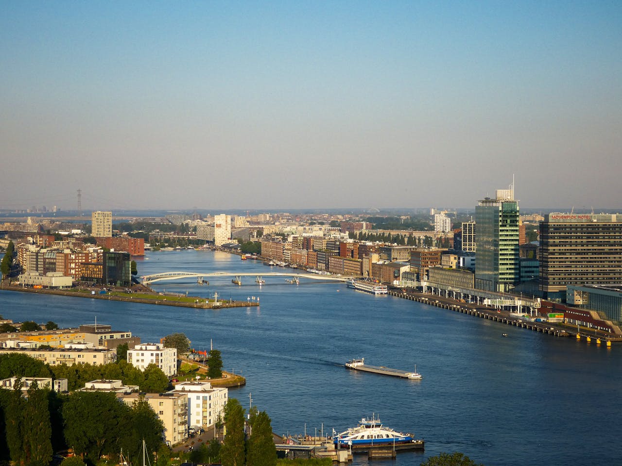 Stunning aerial view of Amsterdam riverfront showcasing modern architecture and waterways.
